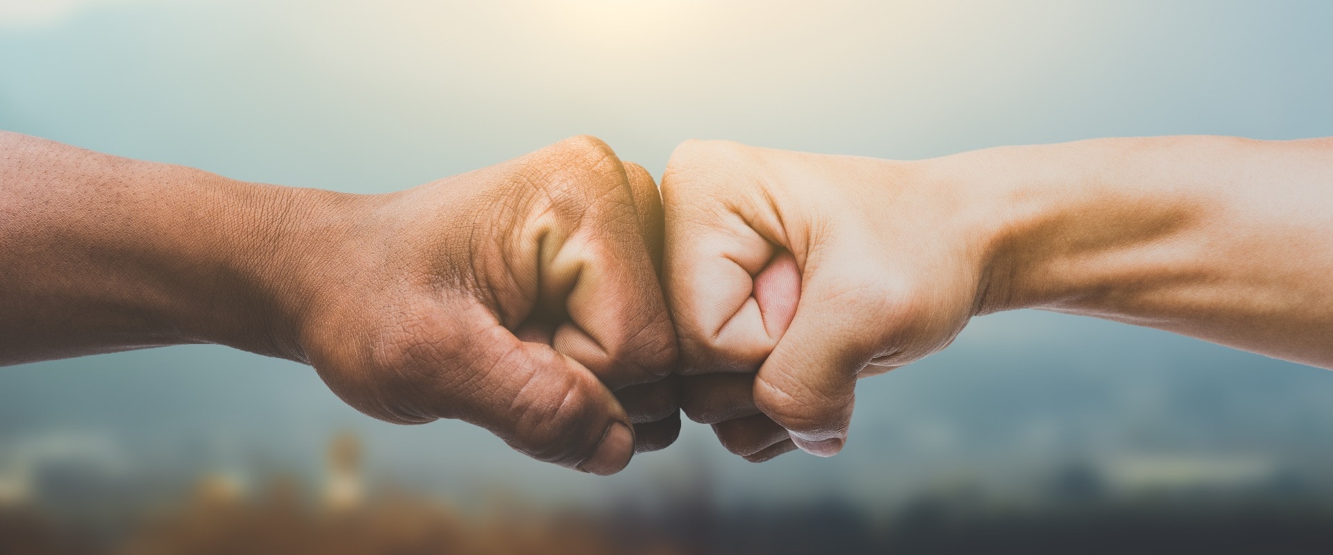 Man giving fist bump in sun rising nature background. power of teamwork concept. vintage tone